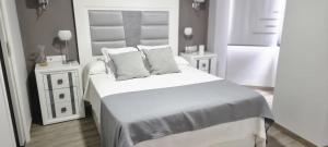 a white bedroom with a bed and two night stands at Virrey del Pino - Apartamento en Baena in Baena