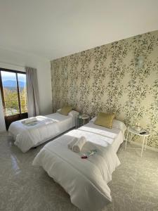 2 bedden in een hotelkamer met bloemenbehang bij El Lago in Cervera de Buitrago