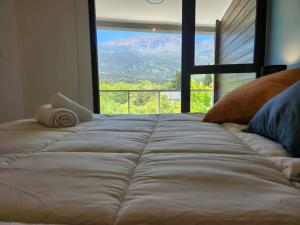 Cama grande en habitación con ventana grande en Andes Departamentos en El Bolsón