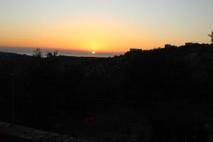 una puesta de sol con la puesta de sol en el horizonte en To Spiti Tou Papa Sto Vouno, en Kamilari