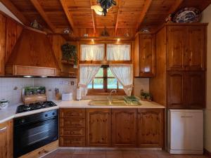 a kitchen with wooden cabinets and a sink and a stove at Kapilio Cottage House in Kapilio +19 photos