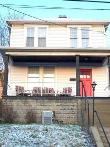 a house with a red door and chairs on the balcony at Beautiful 3 Bedroom Home Cozy Front and Back Porch in Munhall