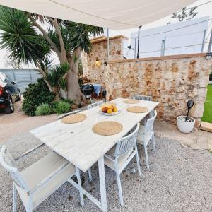 a white table and chairs with a bowl of fruit on it at La Gardana, casa de campo mallorquina in Porreres