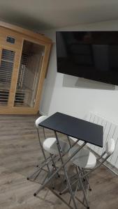einen schwarzen Tisch mit 2 Stühlen und einen Flachbild-TV in der Unterkunft Suite pour les Amoureux_Val d'Europe Disney in Coupvray