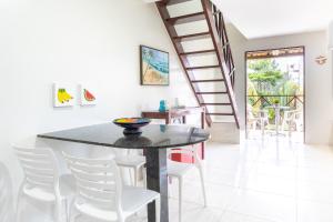 comedor con mesa negra y sillas blancas en Merepe Residence en Porto de Galinhas