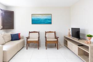 a living room with a couch and a tv at Merepe Residence in Porto De Galinhas
