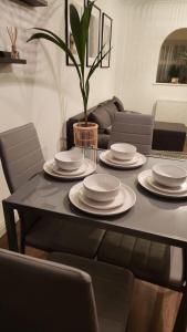 a dining room table with plates and a plant on it at Cosy 2 Bedroom House in Dunstable