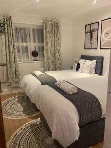 una camera con due letti con lenzuola bianche di Cosy 2 Bedroom House a Dunstable