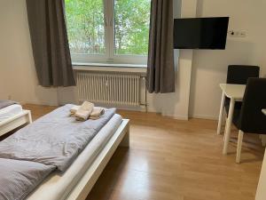 City Apart Düss في دوسلدورف: غرفة نوم بسرير وطاولة وتلفزيون