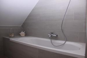 Das Bad ist mit einer Badewanne mit einer Dusche ausgestattet. in der Unterkunft 't Valkennestje in De Haan