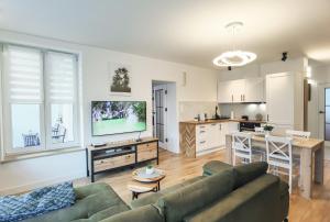 a living room with a couch and a kitchen at Apartament Green Forest in Duszniki Zdrój