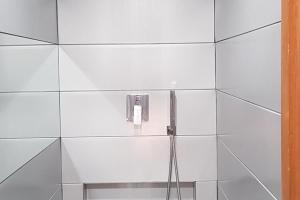 une douche avec un téléphone sur un mur de carrelage blanc dans l'établissement Charming Chalet in Ventron with Terrace, à Ventron