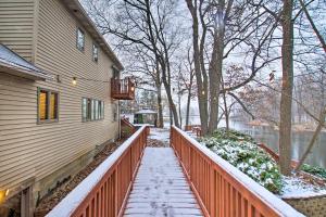 a snow covered sidewalk next to a house with a fence at Ortonville Retreat with 2 Decks and Lake Access! in Ortonville