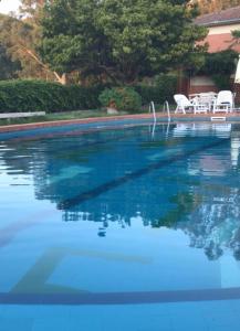 uma piscina com água azul e duas cadeiras brancas em Casa a mare em Calatabiano