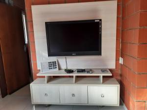 a flat screen tv on a white stand in front of a brick wall at Recanto do Zezé in Gonçalves