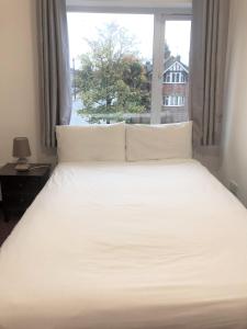 a bedroom with a white bed with a window at Lyttleton Lodge in Uxbridge