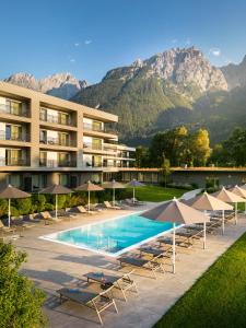ein Hotel mit einem Pool mit Stühlen und Sonnenschirmen in der Unterkunft Dolomitengolf Suites in Lavant