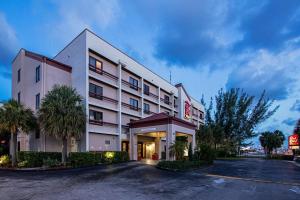 un hotel con un estacionamiento delante de él en Red Roof PLUS Miami Airport en Miami