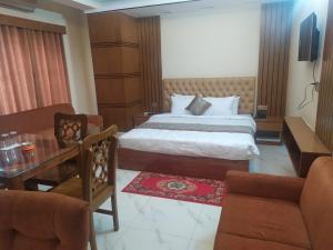 una camera d'albergo con letto, tavolo e sedie di Hotel Blue Moon a Chittagong