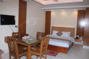 a bedroom with a bed and a table and a television at The Blue Moon Hotel in Chittagong