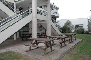 a group of picnic tables in front of a building at Hôtel Premiere Classe Pamiers in Pamiers