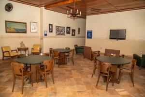 a room with tables and chairs and a flat screen tv at VOA Hotel Caxambu in Caxambu