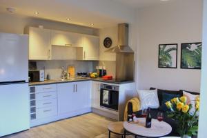 uma cozinha com armários brancos, um sofá e uma mesa em Modern Craigie Apartment em Perth
