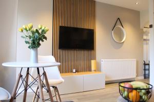 un salon avec une télévision et une table ornée d'un vase de fleurs dans l'établissement Modern Craigie Apartment, à Perth
