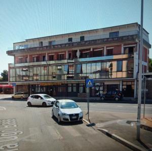 ein Gebäude mit zwei Autos auf einem Parkplatz in der Unterkunft Rosaspina in Grosseto