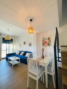 een woonkamer met een tafel en een blauwe bank bij Tríplex Cruz del Mar Beach, Apartamentos Living Sur in Chipiona