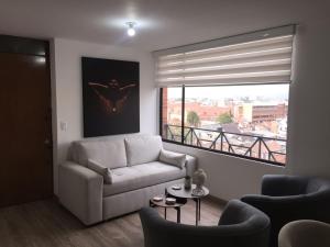 sala de estar con sofá y ventana grande en Macondo-Habitación zona céntrica, en pleno corazón, en Bogotá