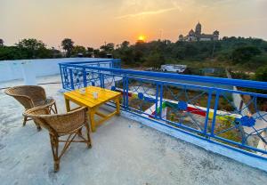 a table and chairs on a balcony with a sunset at Comfort and Cozy in Orchha