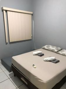 a bed with two towels and a cell phone on it at Casa Park Massangano in Petrolina