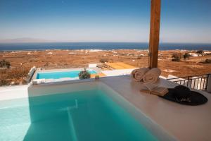a swimming pool with hats and towels on the ledge of a house at North Wind Luxury Suites in Oia