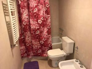 uma casa de banho com um WC e uma cortina de chuveiro vermelha. em Departamentos Eneas Frente al Mar em Mar del Plata