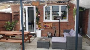 eine Terrasse mit einem Sofa, einem Tisch und einer Bank in der Unterkunft Spacious 2 bedroom house with garden in Edmonton