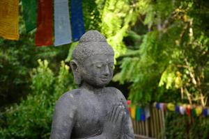 una statua di una persona in piedi in un giardino di Kawai Purapura Yoga Retreat Centre ad Auckland