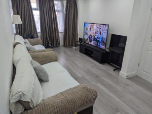 a living room with two couches and a flat screen tv at Spacious 2 bedroom house with garden in Edmonton