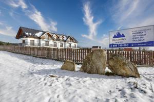 une maison avec des rochers dans la neige à côté d'une clôture dans l'établissement Jagodowy Ski & Spa, à Lasowka