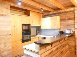 cocina con armarios de madera y encimera negra en Appartement Les Deux Alpes, 5 pièces, 12 personnes - FR-1-546-13, en Les Deux Alpes