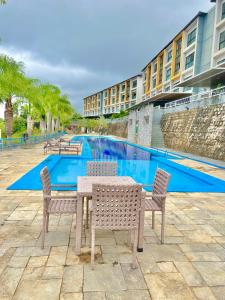 a table and chairs in front of a swimming pool at Lindo Apartamento no Condomínio Alto da Serra Villas de Bananeiras in Bananeiras