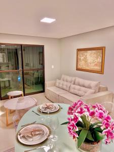 バナネイラスにあるLindo Apartamento no Condomínio Alto da Serra Villas de Bananeirasのリビングルーム(ソファ、ピンクの花のテーブル付)