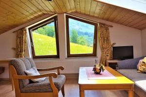 uma sala de estar com um sofá, uma mesa e 2 janelas em 5 Bergpanorama und herrliche alpinen Almlandschaft Nichtraucherdomizil em Schönau am Königssee