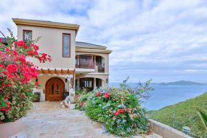 a house with flowers in front of the ocean at Cheerful 3 -bedroom villa with Pool in Tortola Island