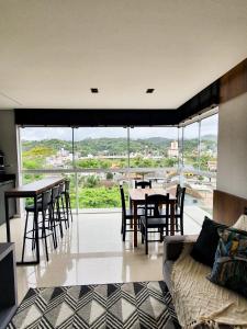 a living room with a table and chairs and a large window at Apartamento ao lado da Vila Germânica in Blumenau