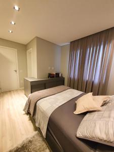a bedroom with two beds and a dresser in it at Apartamento ao lado da Vila Germânica in Blumenau
