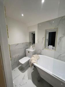 a white bathroom with a tub and a toilet at Newly renovated 3 Bed property - countryside views in Dunstall
