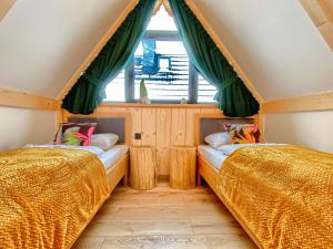 two beds in a room with a window at Domki Tatrzańska Panorama z jacuzzi in Ząb