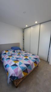 a bedroom with a bed with a colorful quilt on it at Bernal Alquileres in Viedma