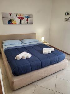 een groot blauw bed met 2 opgerolde handdoeken bij Appartamenti Le Gemme in Napels